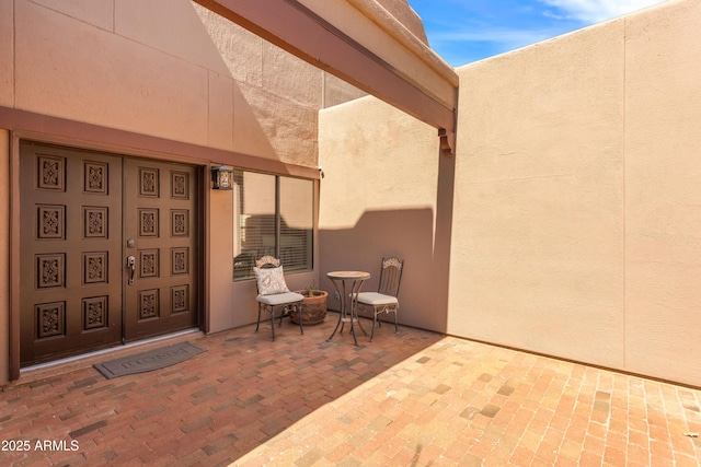 view of exterior entry with a patio area and stucco siding