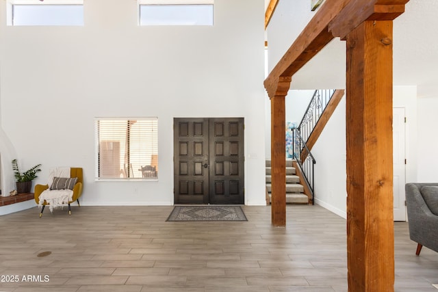 foyer featuring stairs, a high ceiling, wood finished floors, and baseboards