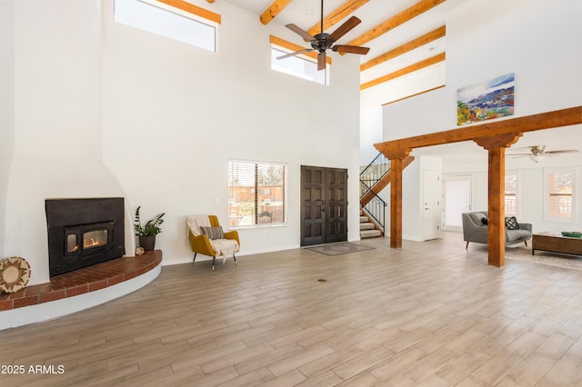 living room with plenty of natural light, stairway, wood finished floors, and a glass covered fireplace