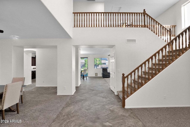 entrance foyer featuring a towering ceiling and carpet