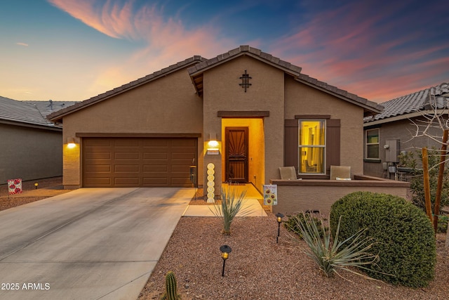 view of front facade with a garage, concrete driveway, a tiled roof, and stucco siding