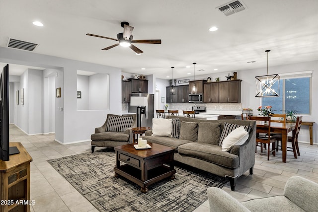 living area featuring baseboards, ceiling fan with notable chandelier, visible vents, and recessed lighting