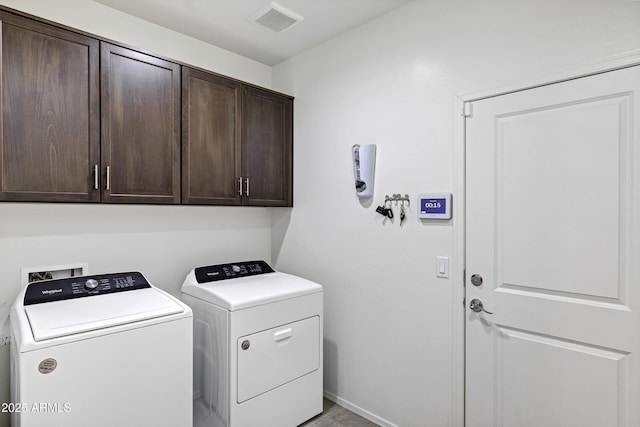 clothes washing area featuring washing machine and dryer, cabinet space, visible vents, and baseboards