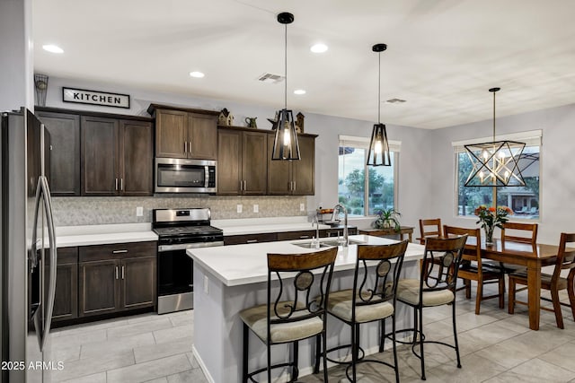 kitchen with tasteful backsplash, visible vents, dark brown cabinetry, light countertops, and stainless steel appliances