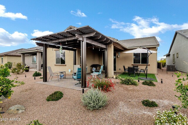 rear view of house featuring central air condition unit, a patio area, a pergola, and stucco siding