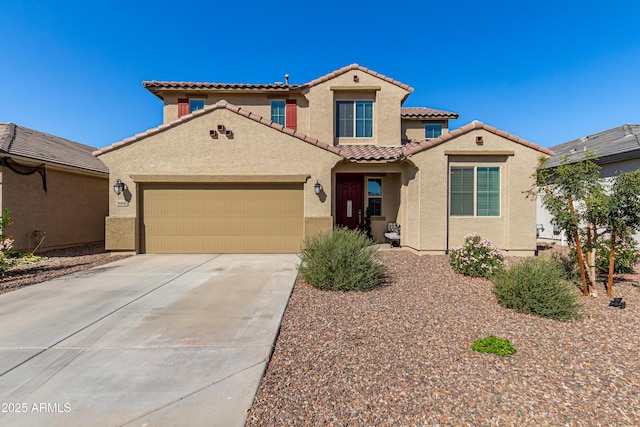 mediterranean / spanish-style home featuring concrete driveway, an attached garage, a tiled roof, and stucco siding