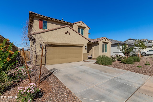 mediterranean / spanish house featuring a garage, fence, concrete driveway, a tiled roof, and stucco siding