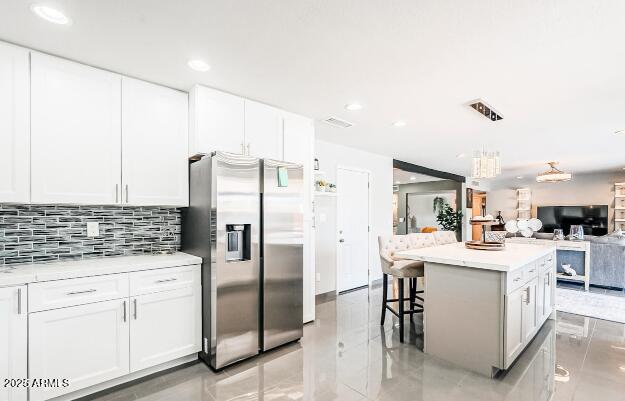 11215 N 37th Ave, Phoenix, AZ 85029 - kitchen with stainless steel fridge, open floor plan, a kitchen island, white cabinets, and decorative backsplash