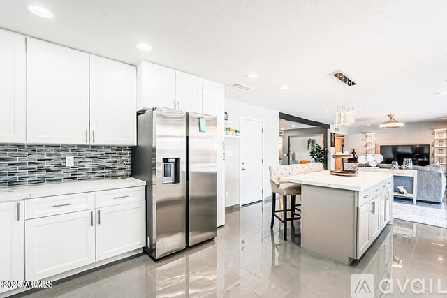 11215 N 37th Ave, Phoenix, AZ 85029 - kitchen with stainless steel fridge, decorative backsplash, light countertops, white cabinetry, and a center island