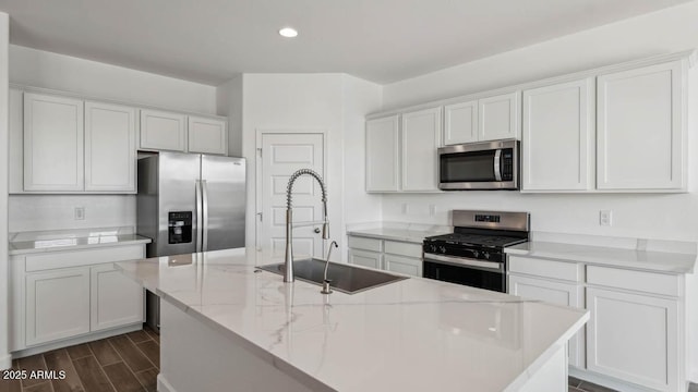 kitchen with appliances with stainless steel finishes, wood finish floors, white cabinetry, and a sink