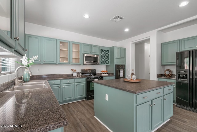 kitchen with dark hardwood / wood-style flooring, sink, a kitchen island, and black appliances