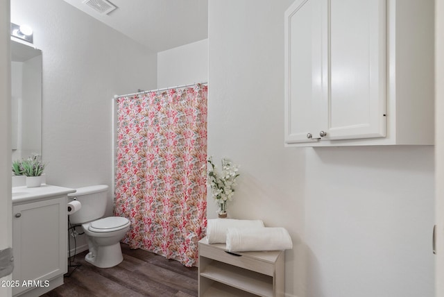 bathroom with hardwood / wood-style flooring, vanity, toilet, and curtained shower