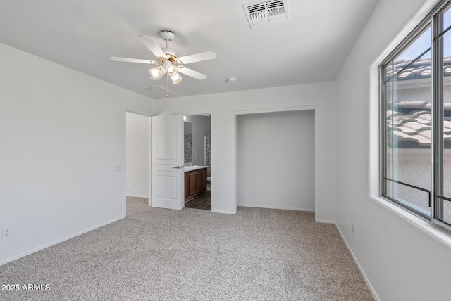 unfurnished bedroom featuring ceiling fan, connected bathroom, and light carpet