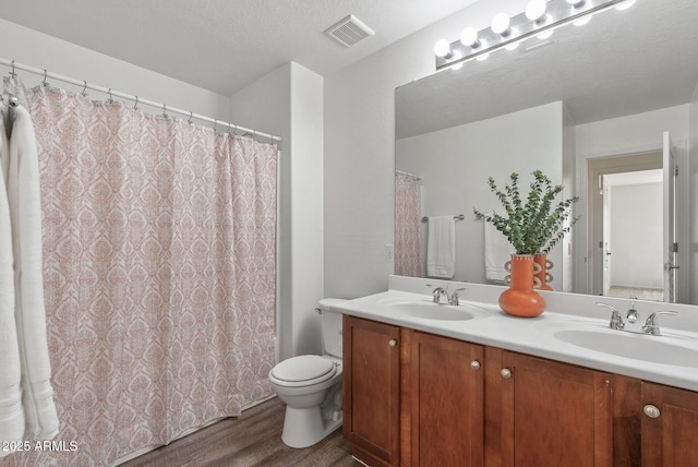 bathroom with vanity, hardwood / wood-style floors, a textured ceiling, and toilet