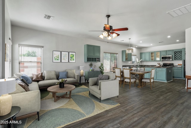 living room featuring dark wood-type flooring and ceiling fan