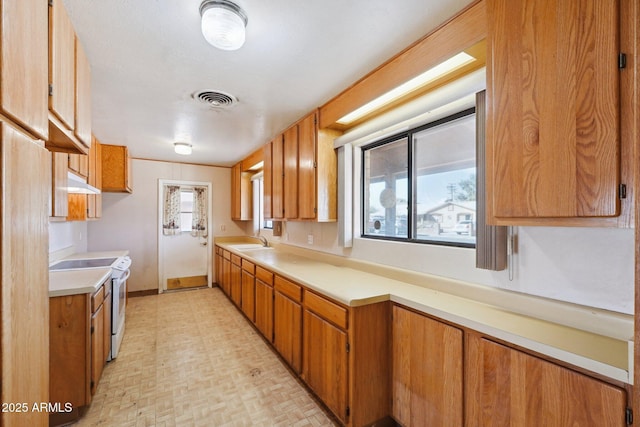 kitchen featuring electric range, visible vents, brown cabinets, light countertops, and a sink