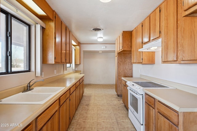 kitchen featuring electric stove, light countertops, visible vents, a sink, and under cabinet range hood