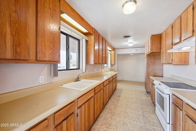 kitchen featuring white range with electric stovetop, light countertops, visible vents, a sink, and under cabinet range hood