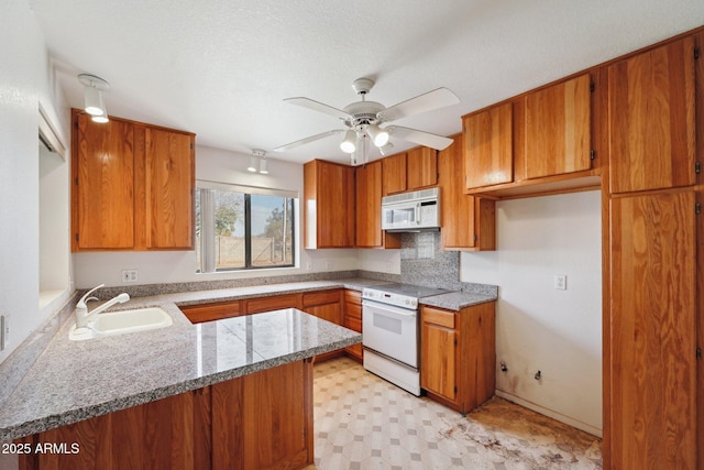 kitchen featuring a peninsula, white appliances, a sink, brown cabinets, and light floors