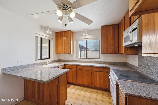 kitchen with a peninsula, white appliances, and brown cabinetry