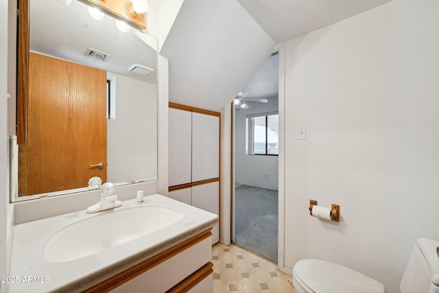 half bath featuring toilet, visible vents, vanity, vaulted ceiling, and tile patterned floors