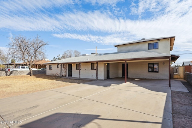 view of front facade featuring fence, concrete driveway, and brick siding