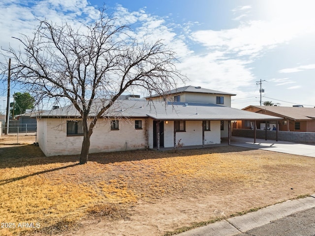 view of front facade featuring driveway, fence, an attached carport, and brick siding