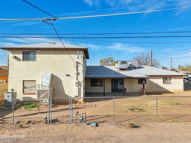 rear view of house featuring fence private yard, a gate, central AC, and brick siding