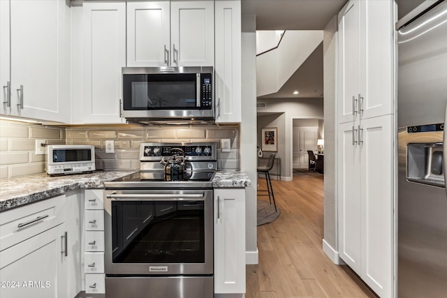 kitchen featuring light hardwood / wood-style floors, light stone countertops, stainless steel appliances, and white cabinetry