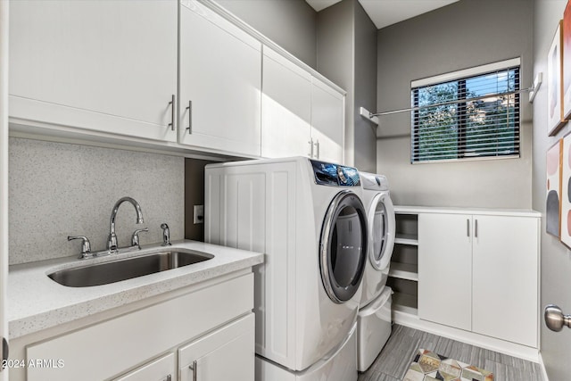 laundry room featuring light hardwood / wood-style floors, cabinets, separate washer and dryer, and sink