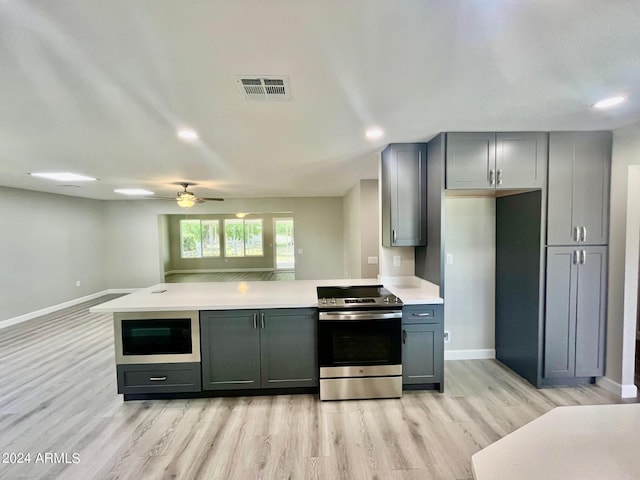 kitchen featuring visible vents, light wood finished floors, a peninsula, light countertops, and stainless steel range with electric stovetop