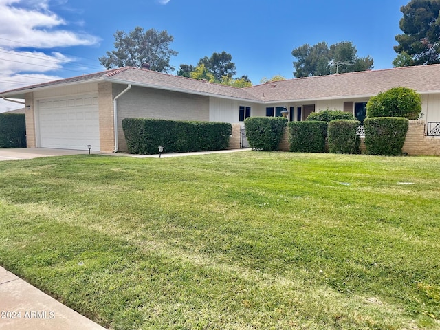 view of front of home featuring brick siding, driveway, a front lawn, and an attached garage