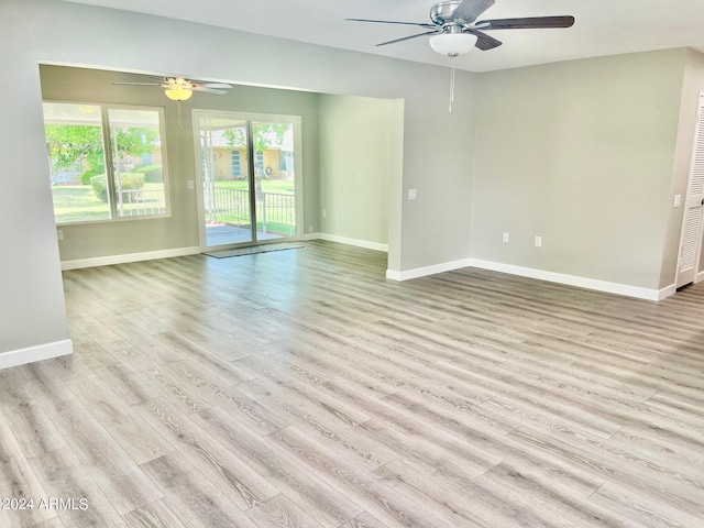 empty room featuring baseboards, wood finished floors, and a ceiling fan
