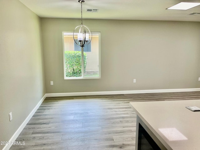 unfurnished dining area with visible vents, light wood-style floors, and a chandelier