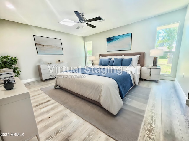 bedroom featuring a ceiling fan, light wood-style flooring, visible vents, and baseboards