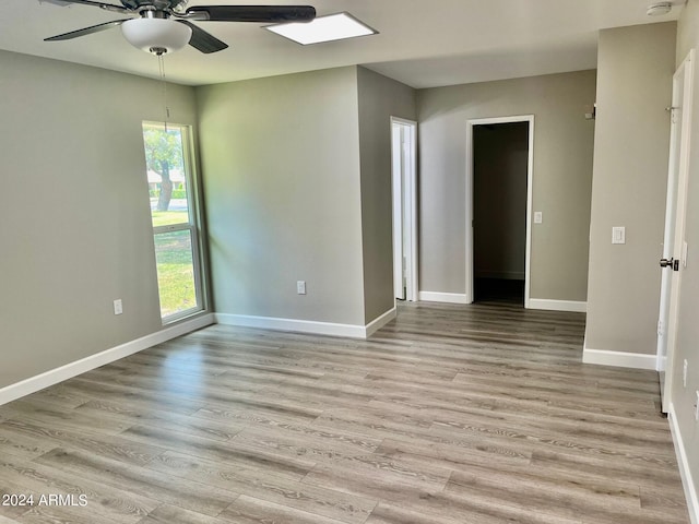 empty room featuring light wood-style flooring, a ceiling fan, and baseboards