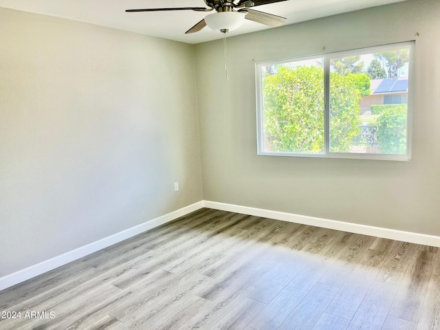 unfurnished room with wood finished floors, a ceiling fan, and baseboards