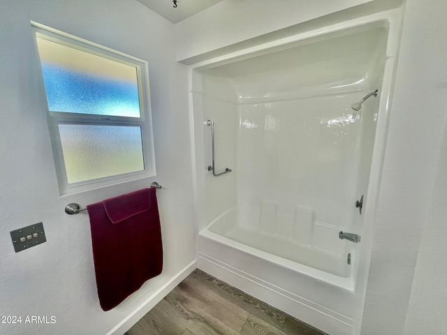 full bath featuring bathing tub / shower combination, wood finished floors, and baseboards