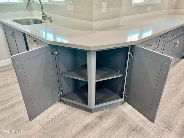 interior details featuring dishwasher, wood finished floors, and a sink