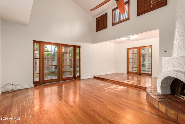 unfurnished living room with french doors, hardwood / wood-style floors, and a high ceiling