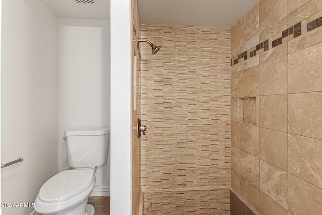 bathroom featuring a tile shower and toilet