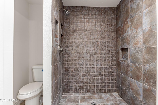 bathroom with toilet and tiled shower