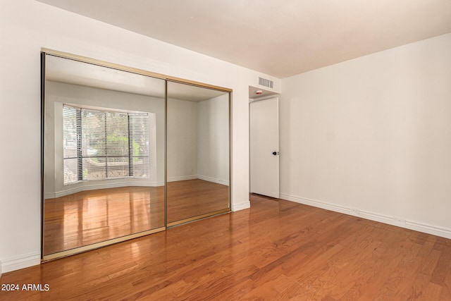 unfurnished bedroom with hardwood / wood-style floors and a closet