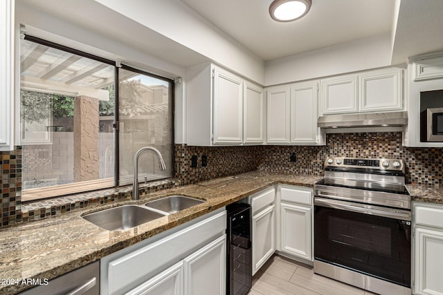 kitchen with white cabinetry, appliances with stainless steel finishes, sink, and dark stone counters