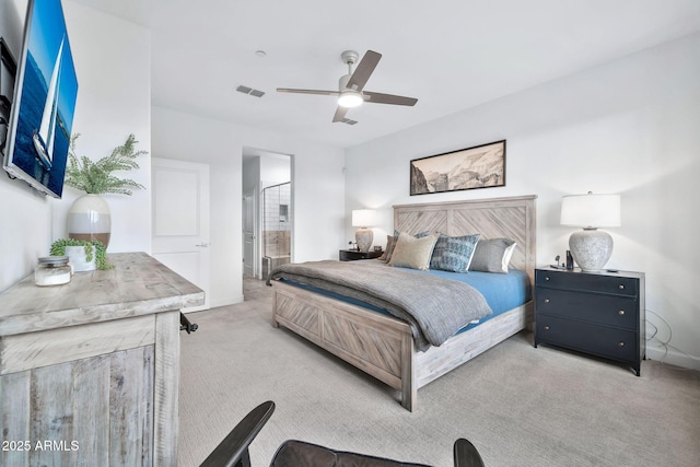 bedroom with ceiling fan, light colored carpet, and ensuite bathroom