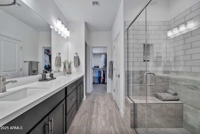 bathroom with a shower with shower door and vanity