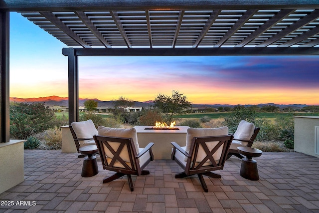 patio terrace at dusk featuring a pergola and a fire pit