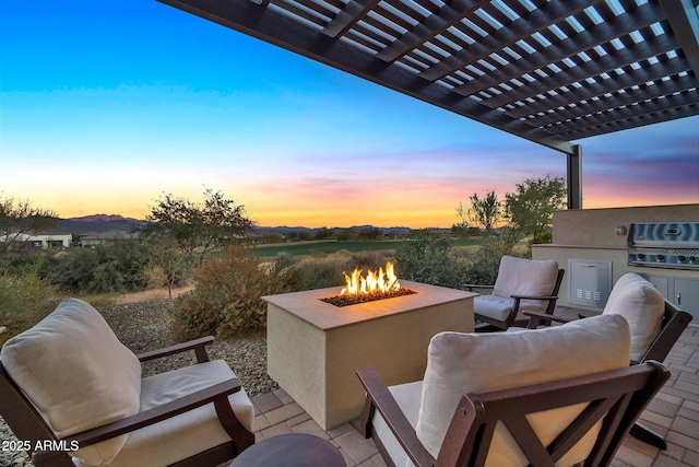 patio terrace at dusk featuring grilling area, a pergola, area for grilling, and a fire pit