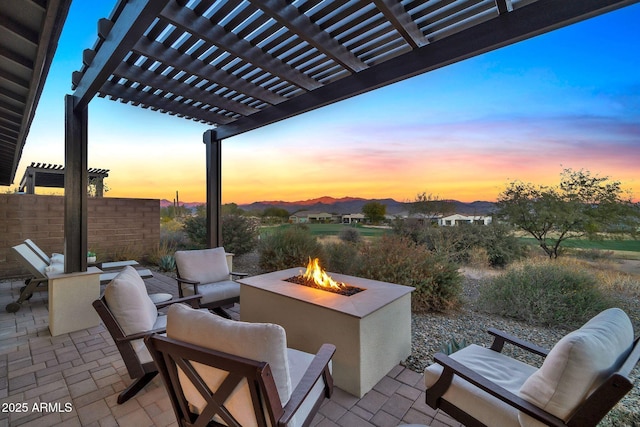 patio terrace at dusk with an outdoor fire pit and a pergola