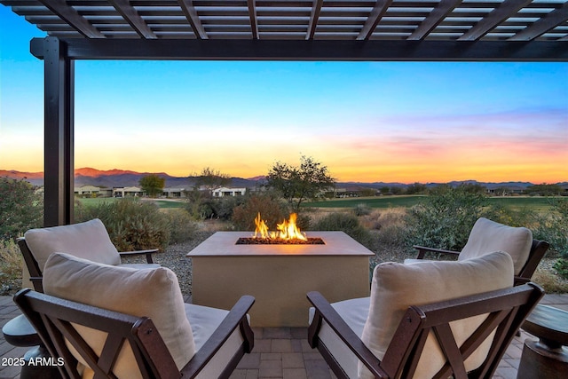 patio terrace at dusk featuring an outdoor fire pit and a pergola